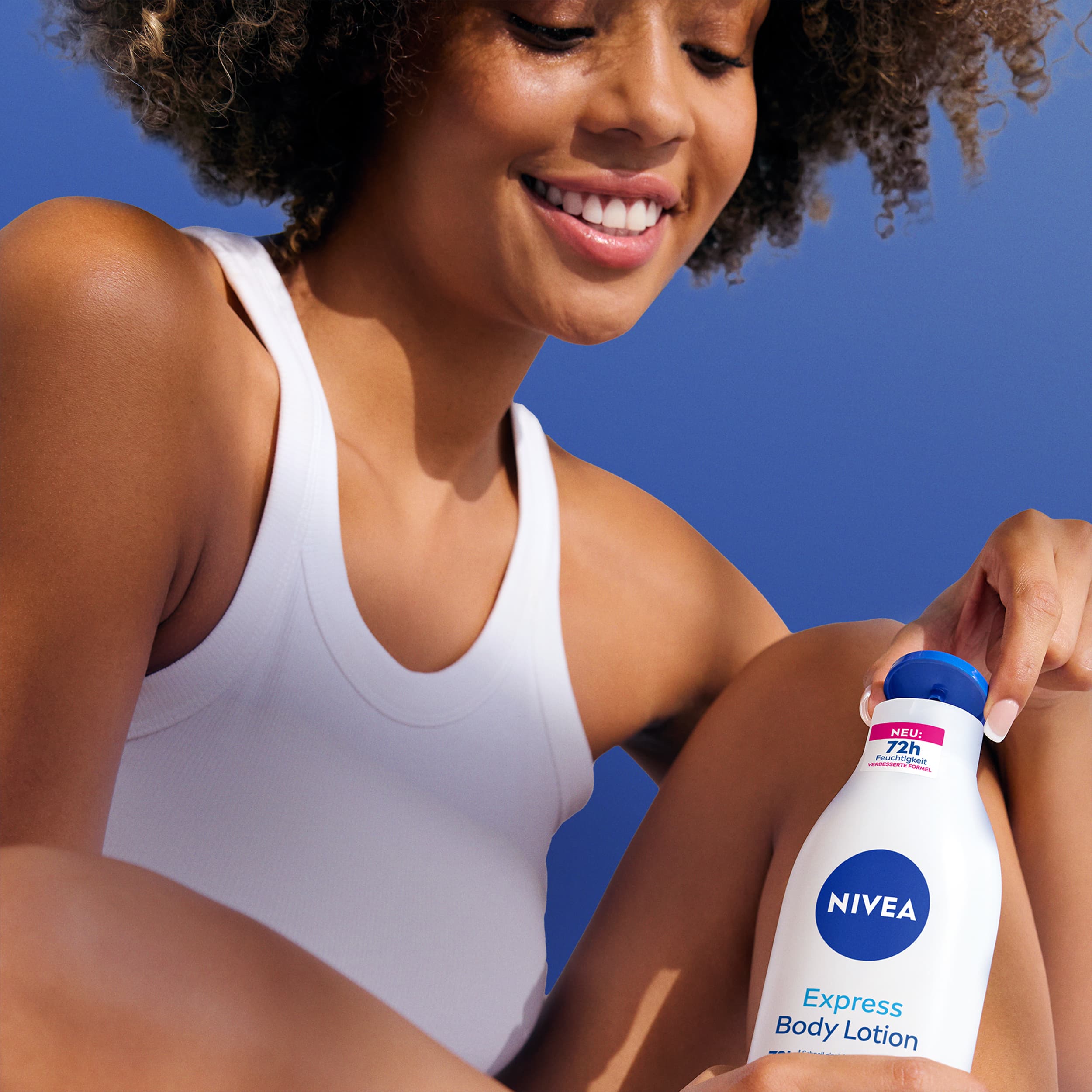 Woman with a body lotion bottle on blue background