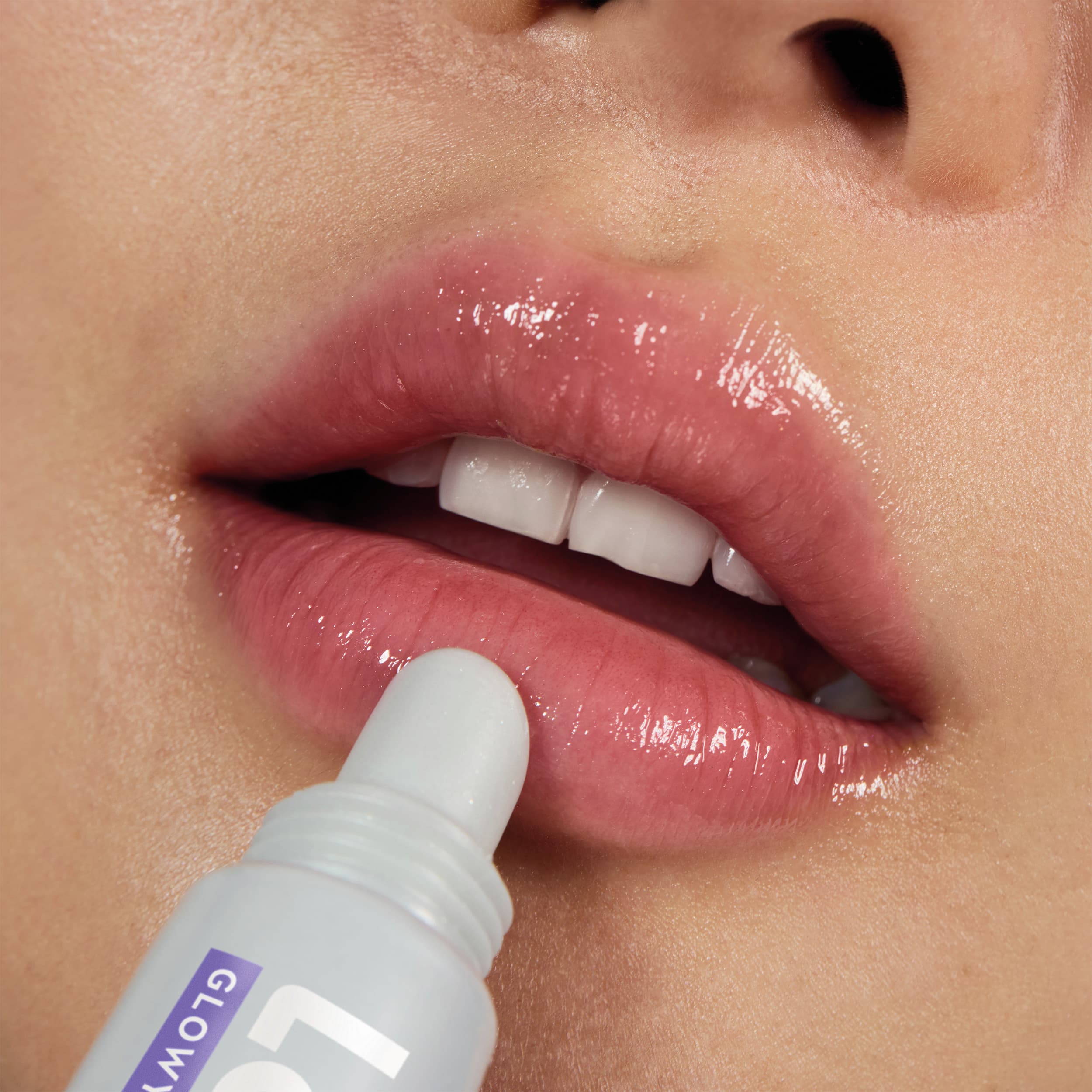 Woman's lips applying lip gloss from a white tube