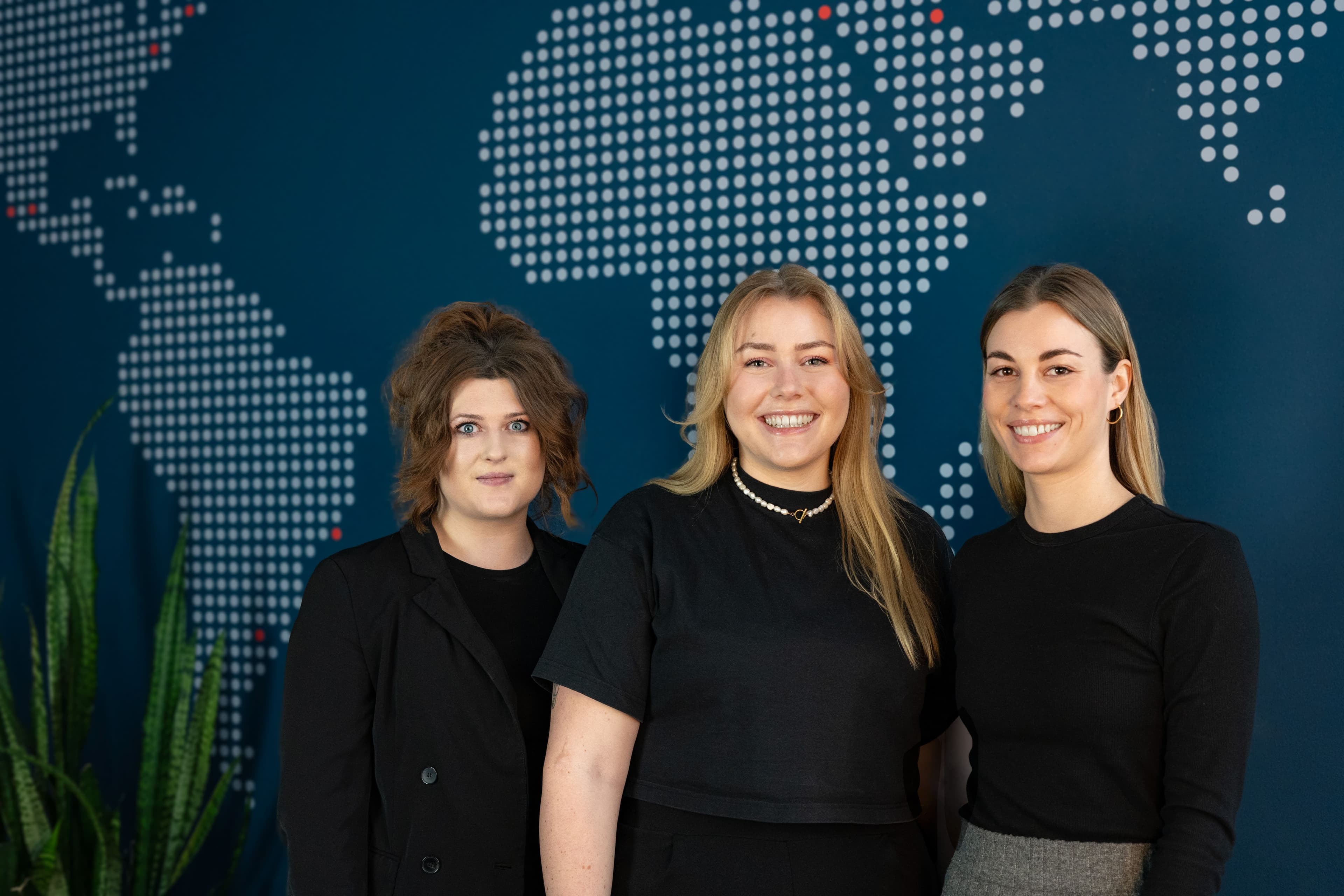 Three women in black shirts on a blue background